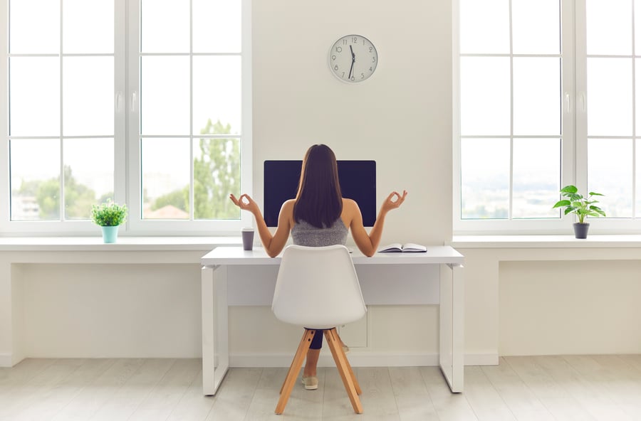 Employee working from home sitting and meditating in front of her computer.